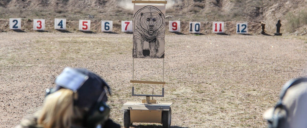shooters aiming at a bear target at an outdoor range