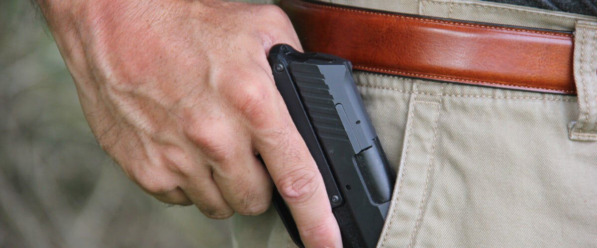 person pulling a handgun from a pants pocket